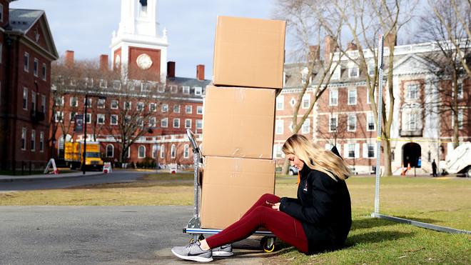 Student sits with her belongings before returning home to Florida from Massachusetts for the rest of the semester, Getty Images.