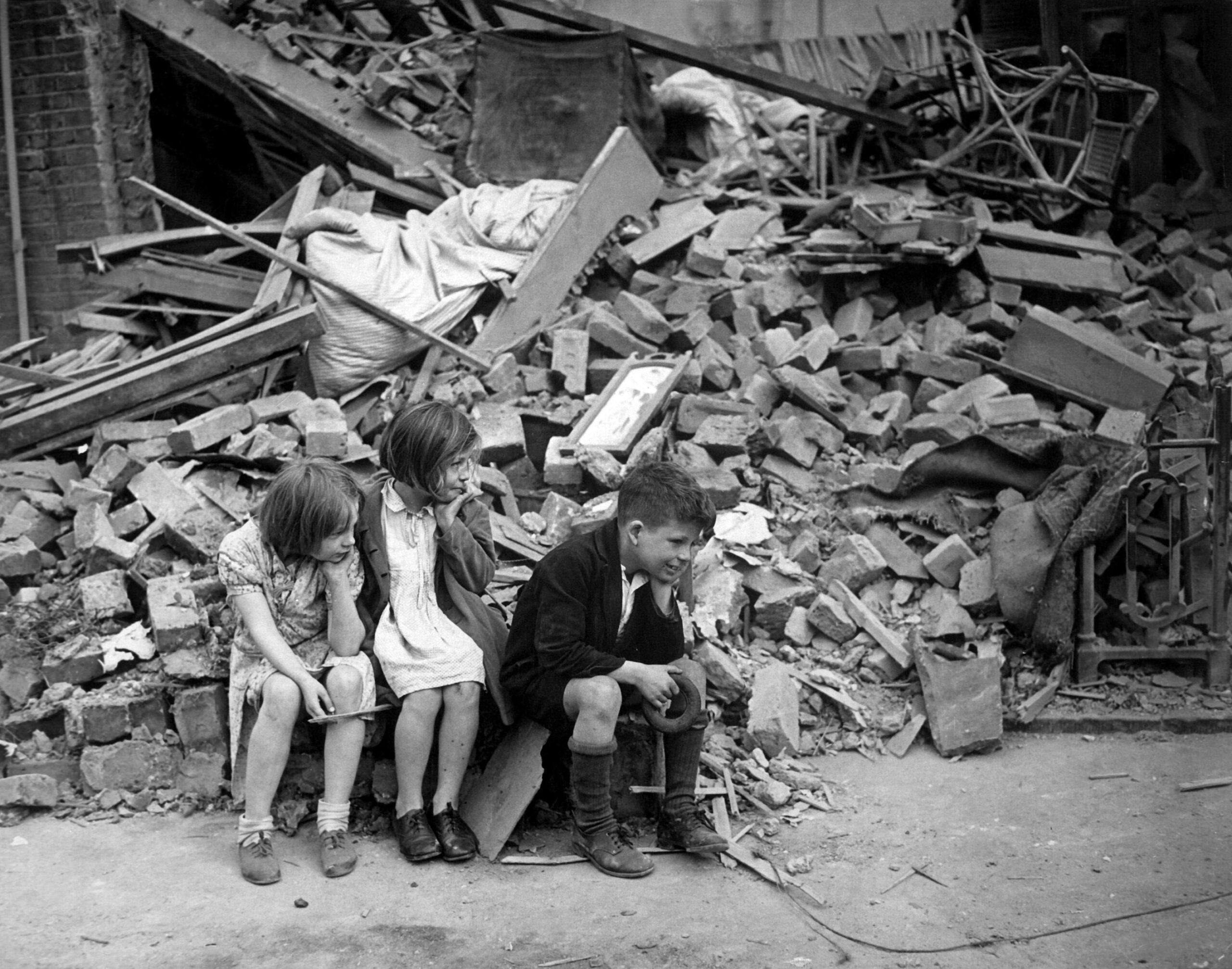 Children of an eastern suburb of London, who have been made homeless by the random bombs of the Nazi night raiders, waiting outside the wreckage of what was their home. September 1940. New Times Paris Bureau Collection. (USIA)<br /> Exact Date Shot Unknown<br /> NARA FILE #: 306-NT-3163V<br /> WAR & CONFLICT BOOK #: 1009