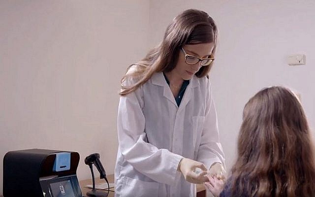A nurse taking a blood test, with the OLO device developed by Sight Diagnostics in the background (YouTube screenshot)