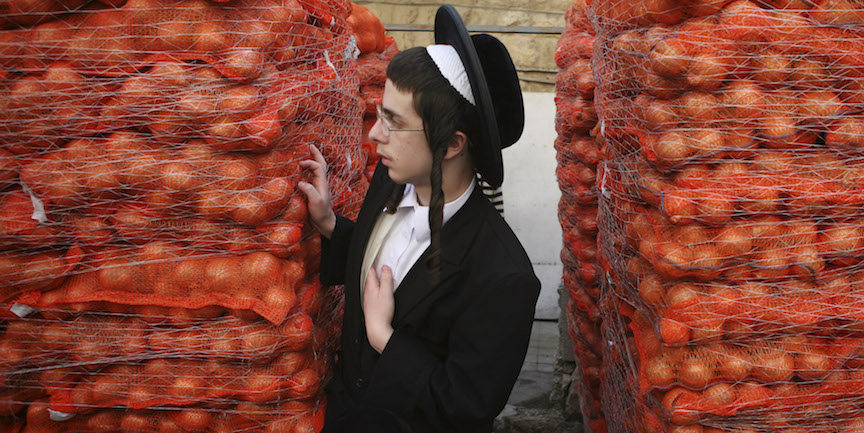 A haredi youth stands next to piles of potatoes in Jerusalem (Photo credit: Matanya Tausig/Flash90)