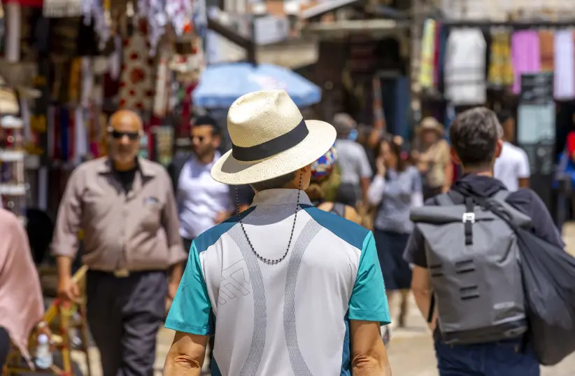 A man wearing a hat during a hot sunny summer day walks near the Tower of David in Jerusalem Old City on June 23, 2022. (photo credit: OLIVIER FITOUSSI/FLASH90)