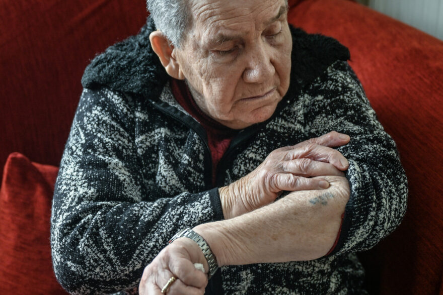 Holocaust survivor Naki Bega looks at her Auschwitz-Birkenau serial-number digits tattooed on her skin, as she poses at her daughter’s home in Athens, Greece, on March 14, 2023. (Louisa Gouliamaki/AFP)