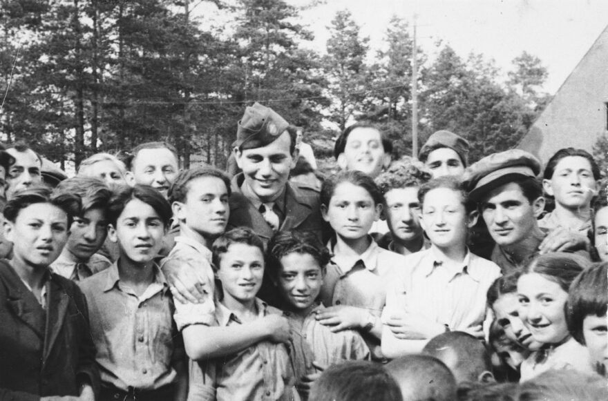 Illustrative: Children at the Foehrenwald DP camp gather around a US soldier. (United States Holocaust Memorial Museum, courtesy of Larry Rosenbach)