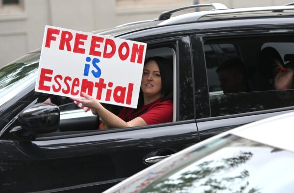 A driver holds out a sign as hundreds of people gather to protest the lockdown in spite of shelter-in-place rules still being in effect at California’s state capitol building in Sacramento, Calif., on April 20, 2020. (Josh Edelson/AFP via Getty Images)