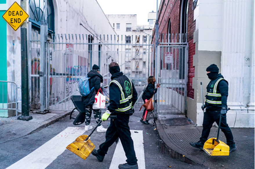 Urban Alchemy employees pick up trash while people gather belongings in the Tenderloin neighborhood. | Melina Mara/The Washington Post via Getty Images