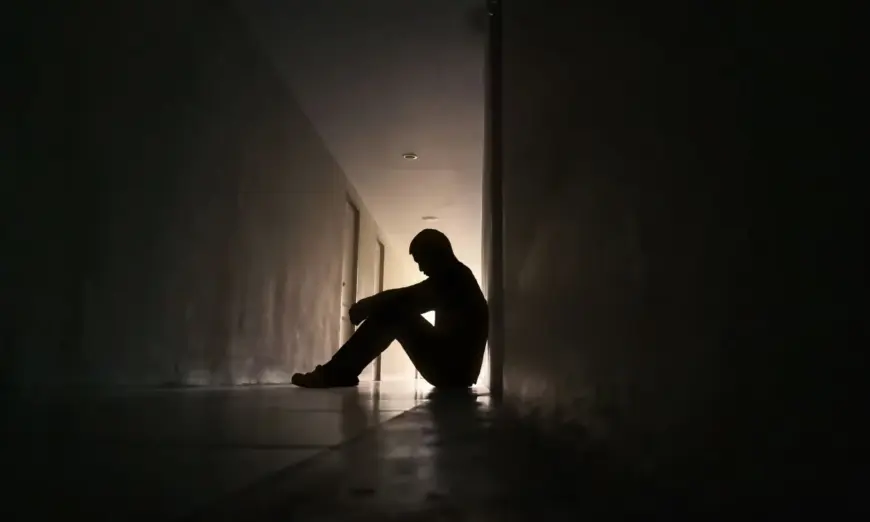 Silhouette of depressed man sitting on walkway of residence building (Aonprom Photo/Shutterstock)