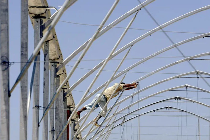 Roberto SCHMIDT / AFP - A Palestinian worker unbolts a metal framework as he and others help dismantle Israeli owned greenhouses near the New Pe'at Sade settlement of the Gush Katif settlement bloc in southern Gaza Strip, July 29, 2005