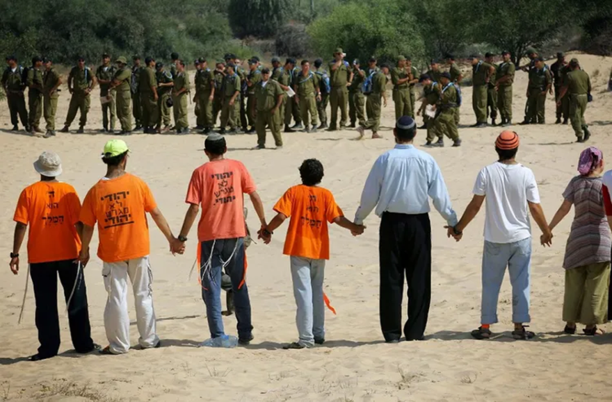 DAVID FURST / AFP - Israeli settlers link arms to prevent Israeli soldiers from entering the rear entrance to the southern Gaza Strip Gush Katif settlement of Neve Dekalim, 15 August, 2005.