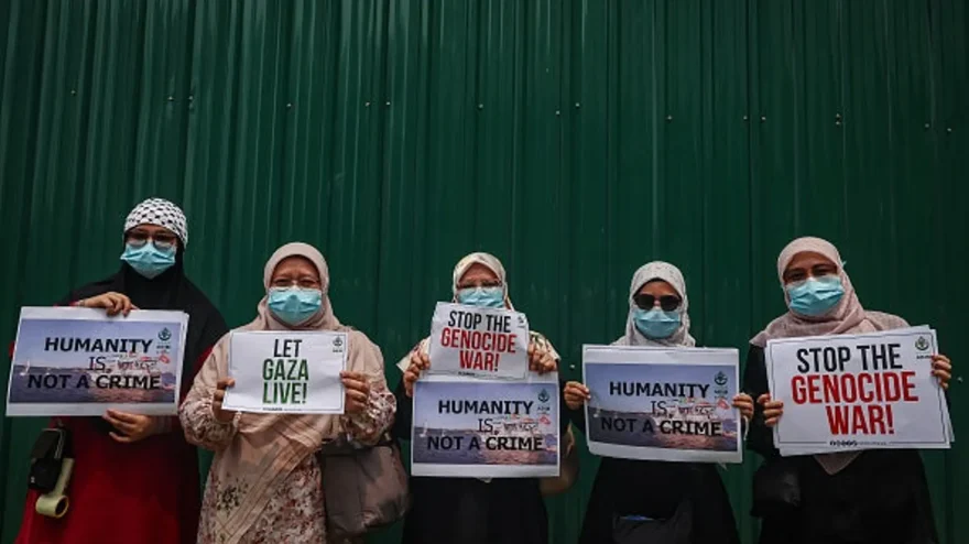 Women at an anti-Israel rally on Oct. 9, 2026, in Kuala Lumpur, Malaysia, hold placards with messages created by the leaders of the Global Alliance for Palestine for protests around the country. The messages read "Humanity Is Not a Crime," "Let Gaza Live" and "Stop the Genocide War." (Annice Lyn/Getty Images)